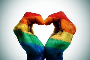 man hands patterned as the rainbow flag forming a heart, symbolizing gay love