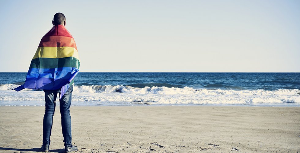 Person vid havet med regnbågsflagga